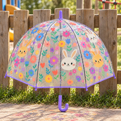 Clear dome umbrella printed with bunny faces and colourful flowers, purple trim and hooked handle, standing against a wooden fence outdoors. 1