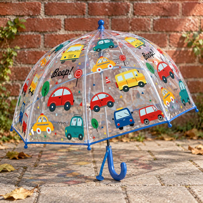 Clear dome umbrella printed with colourful cartoon cars, buses and taxis, blue trim and handle, standing on paving beside a brick wall. 3