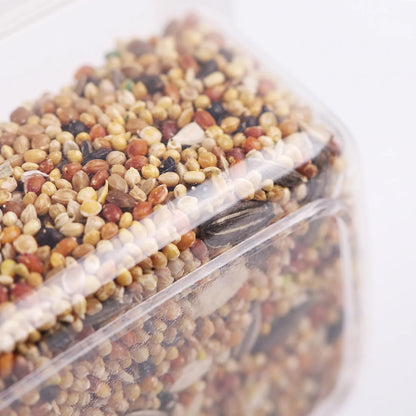 Close-up of the transparent plastic wall of the feeder, showing the mixed seeds and husks packed inside. 3