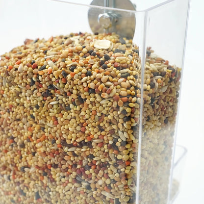 Close-up of the clear plastic seed hopper filled with mixed seeds, showing the metal washer and bolt behind. 3