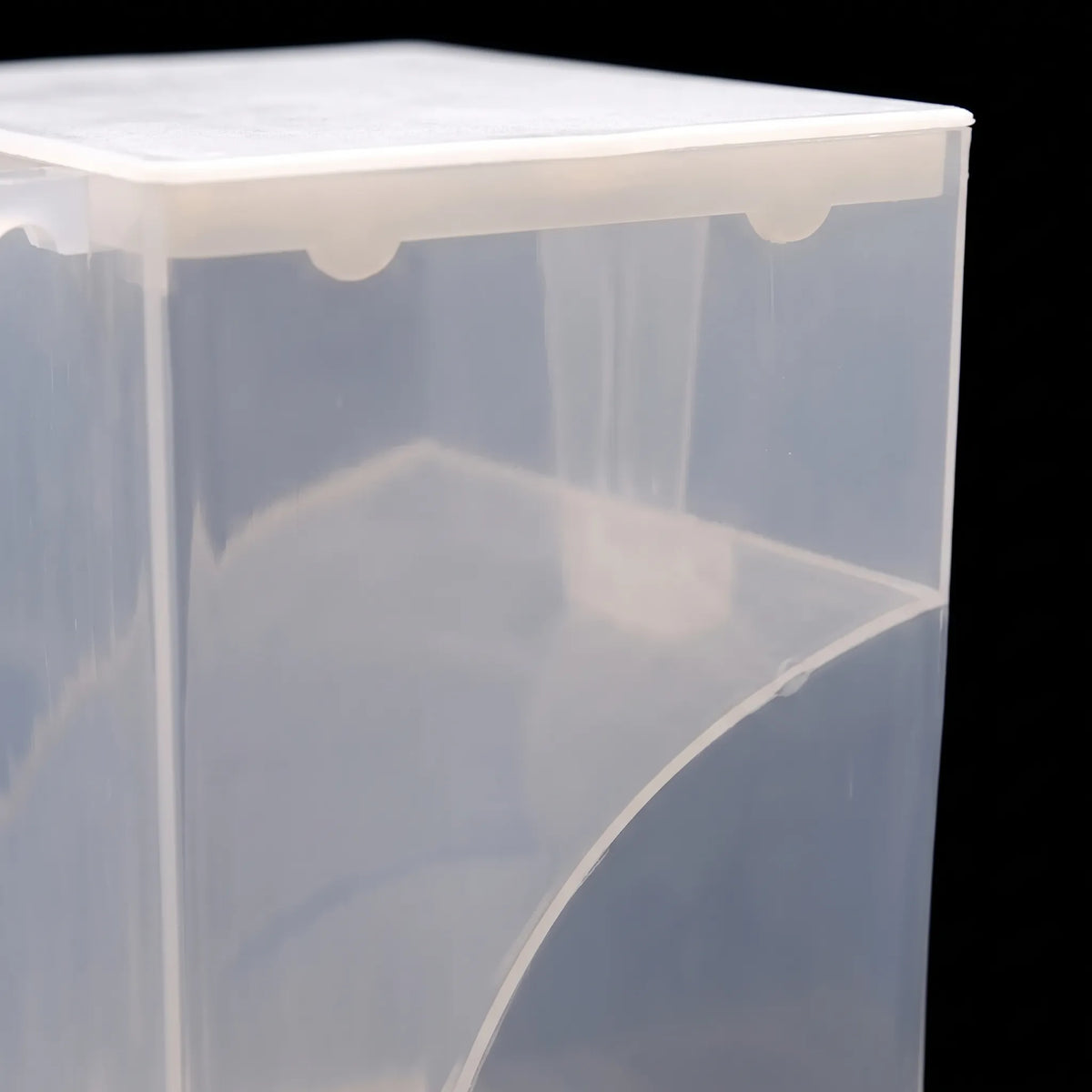 Close-up of the translucent plastic upper corner, showing the white lid edge, small notches and the curved inner panel, against a black background. 3