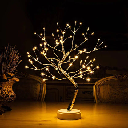 Lit tree lamp on a white round base, standing on a polished table beside a dried flower vase 2