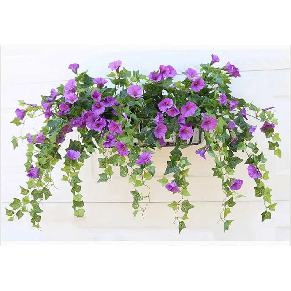 Purple flowers and long trailing green vines spilling from a window-style planter box mounted against a white wooden wall. 6