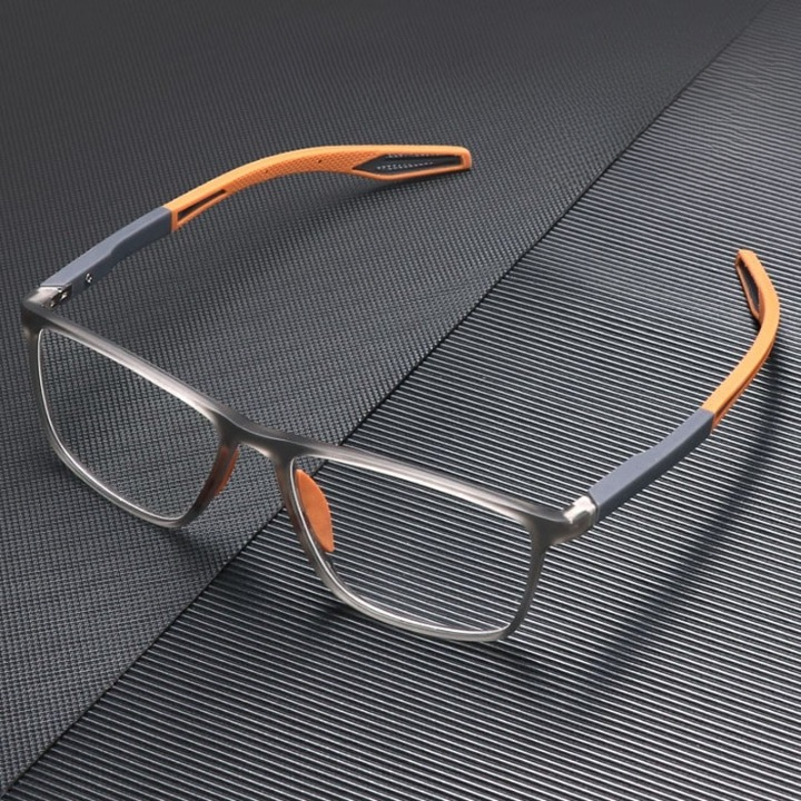 Grey and orange glasses resting on a dark ridged textured surface, seen from above at an angle 2