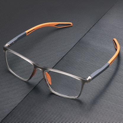 Grey and orange glasses resting on a dark ridged textured surface, seen from above at an angle 2
