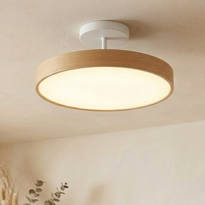Pale oak-effect round light with a white canopy and stem, giving a soft warm glow on a cream ceiling. 5