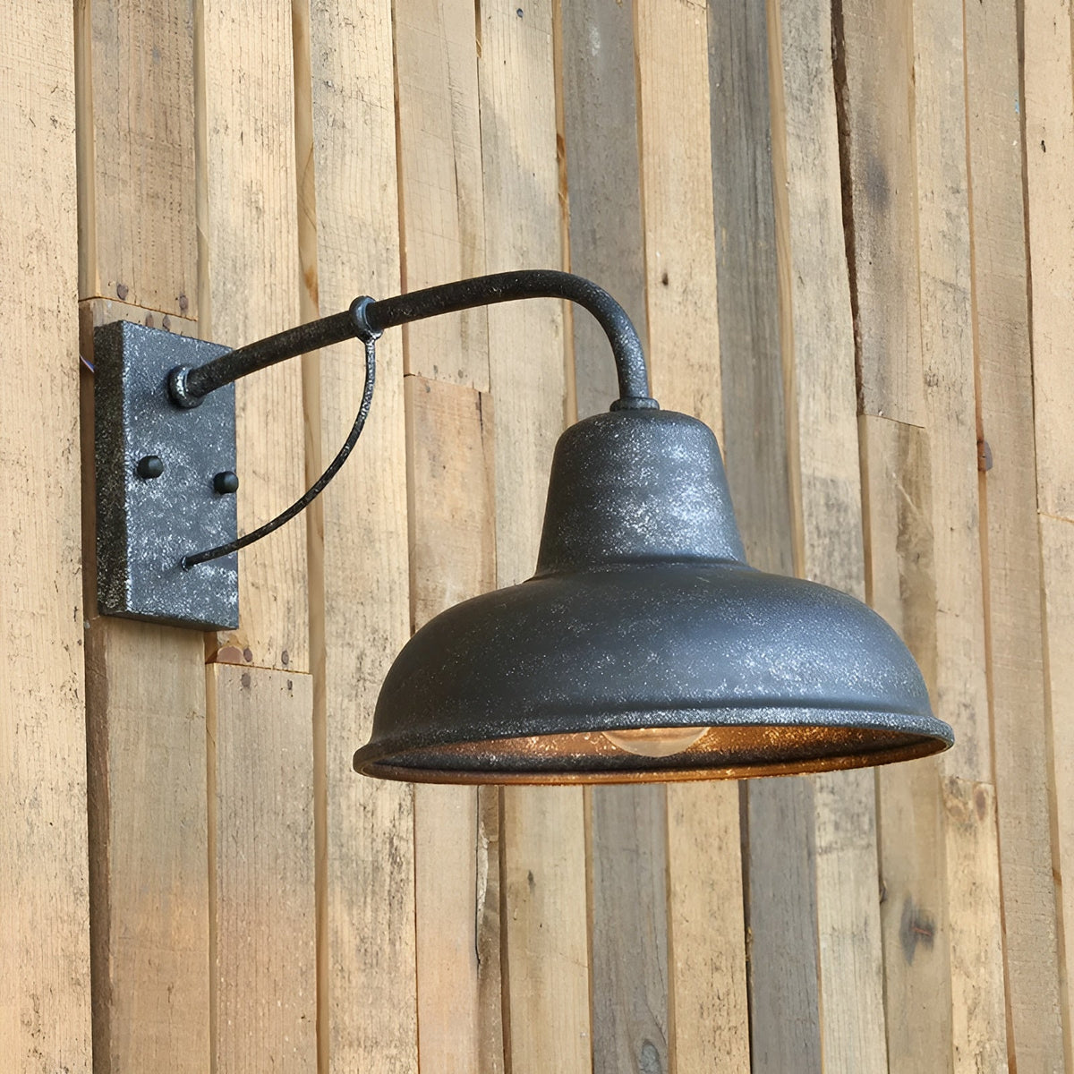 Weathered dark grey wall light with a speckled antique finish, mounted on a rustic vertical wooden plank wall. 2