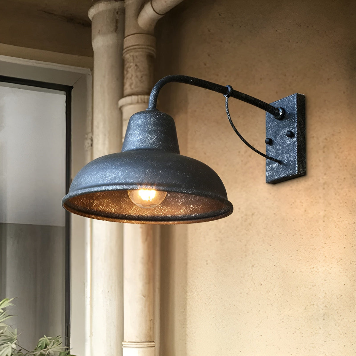 Antique grey speckled wall light glowing warmly on a rendered wall next to a window and a drainpipe. 6