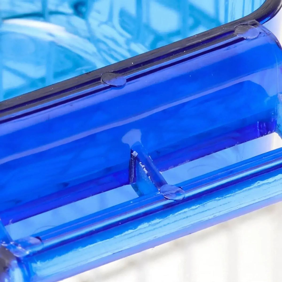 Close-up of the blue plastic perch bar and its supports at the front of the bath, showing the moulded edges. 3