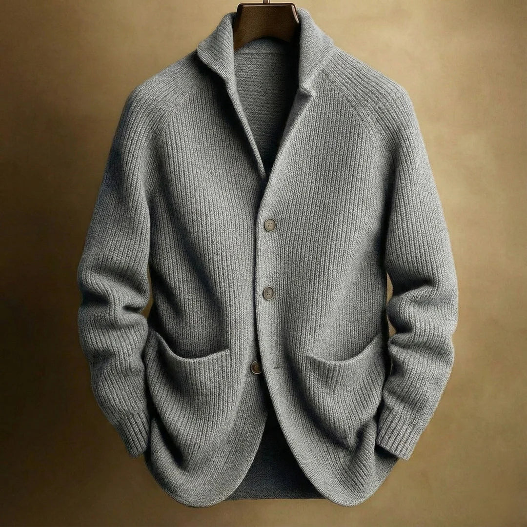 Grey ribbed knit cardigan with raglan sleeves and patch pockets, hanging on a wooden hanger against a golden background 5