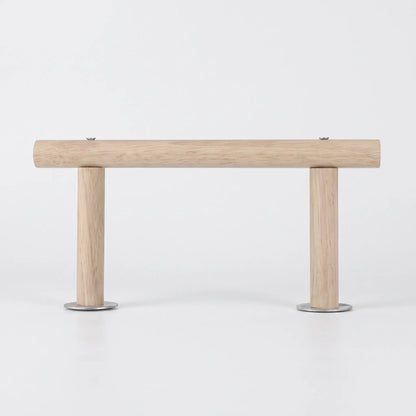 Side view of the light wooden perch on a plain white background, a horizontal bar held by two short legs with metal discs. 1