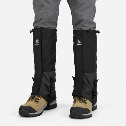 All-black gaiters with a two-tone panel and underfoot straps, worn over grey trousers and tan hiking boots on a white background. 8