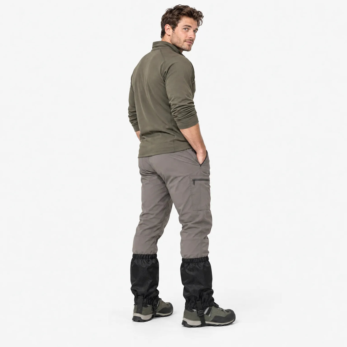 Man in an olive top and grey trousers looking over his shoulder, showing the back of black gaiters worn over boots. 4
