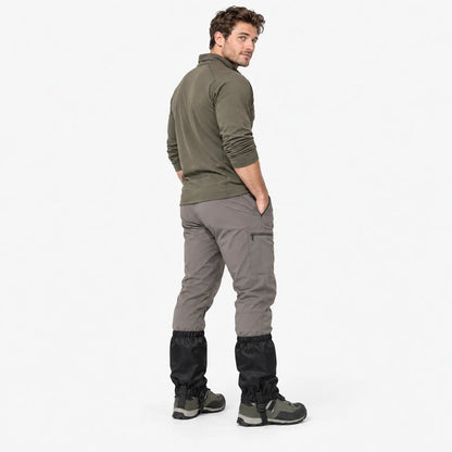 Man in an olive top and grey trousers looking over his shoulder, showing the back of black gaiters worn over boots. 4