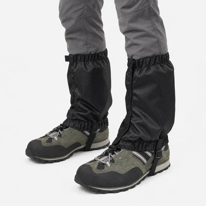 Black gaiters on grey trousers and olive hiking boots, angled view showing the side closure and underfoot strap, white background. 5
