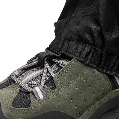 Close-up of the black gaiter hem clipped to the boot laces with a small plastic hook, showing the ripstop fabric texture. 6