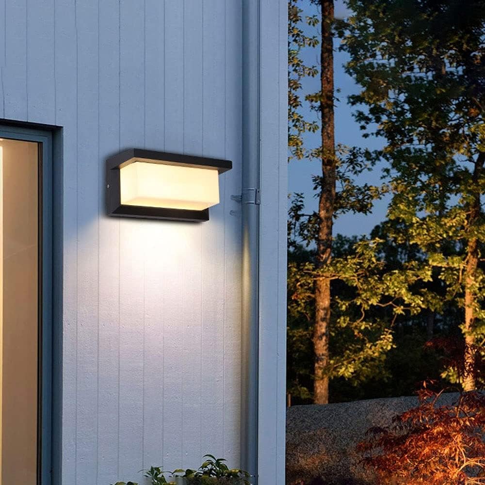 Light on pale panelled exterior wall beside a drainpipe, with trees in the background at night 6