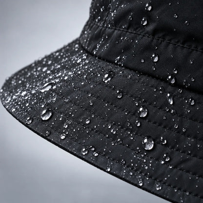 Close-up of the black hat's stitched brim and crown, covered in water droplets showing the water-repellent fabric. 6