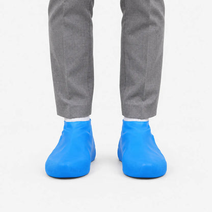 Front view of blue shoe covers worn over shoes with white socks and grey trousers, against a plain white background. 2