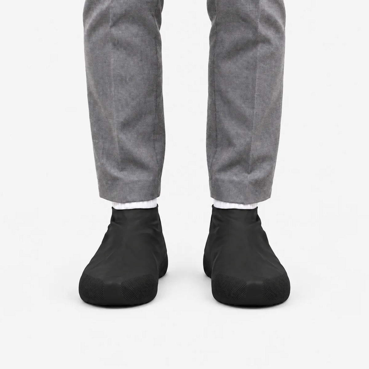 Front view of black shoe covers worn with white socks and grey trousers, against a plain white background. 4