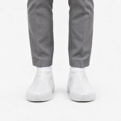 Front view of translucent white shoe covers worn with white socks and grey trousers, showing the patterned grip at the toe. 8