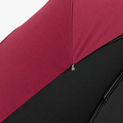 Close-up of a burgundy canopy seam and a metal rib tip, with the black lining visible beneath the fabric. 4