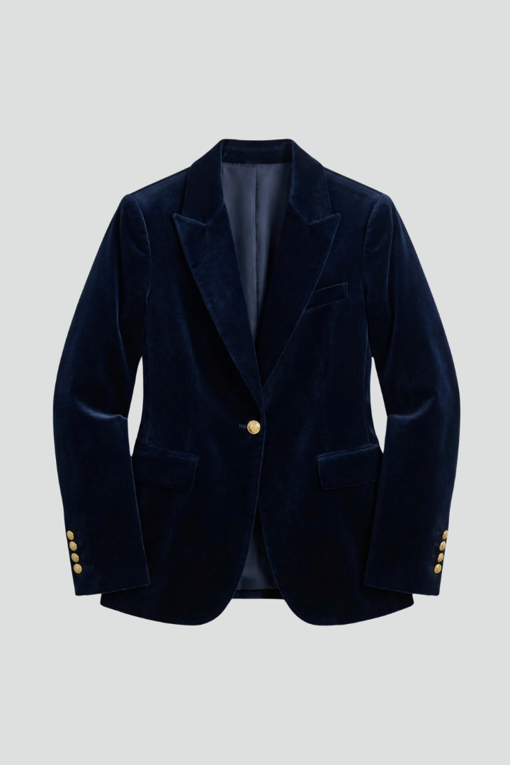 Navy velvet blazer laid flat, showing peak lapels, one gold button, flap pockets and buttoned cuffs 1