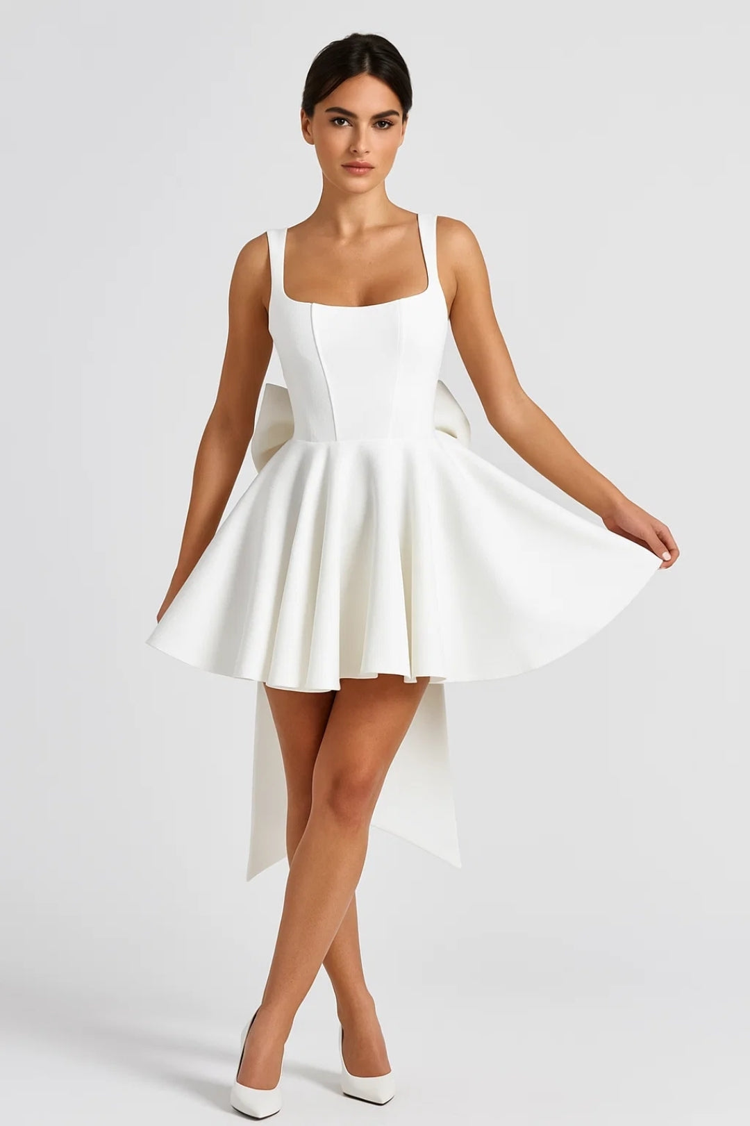 Model in the white dress, front view, holding out the full flared skirt with white heels 3