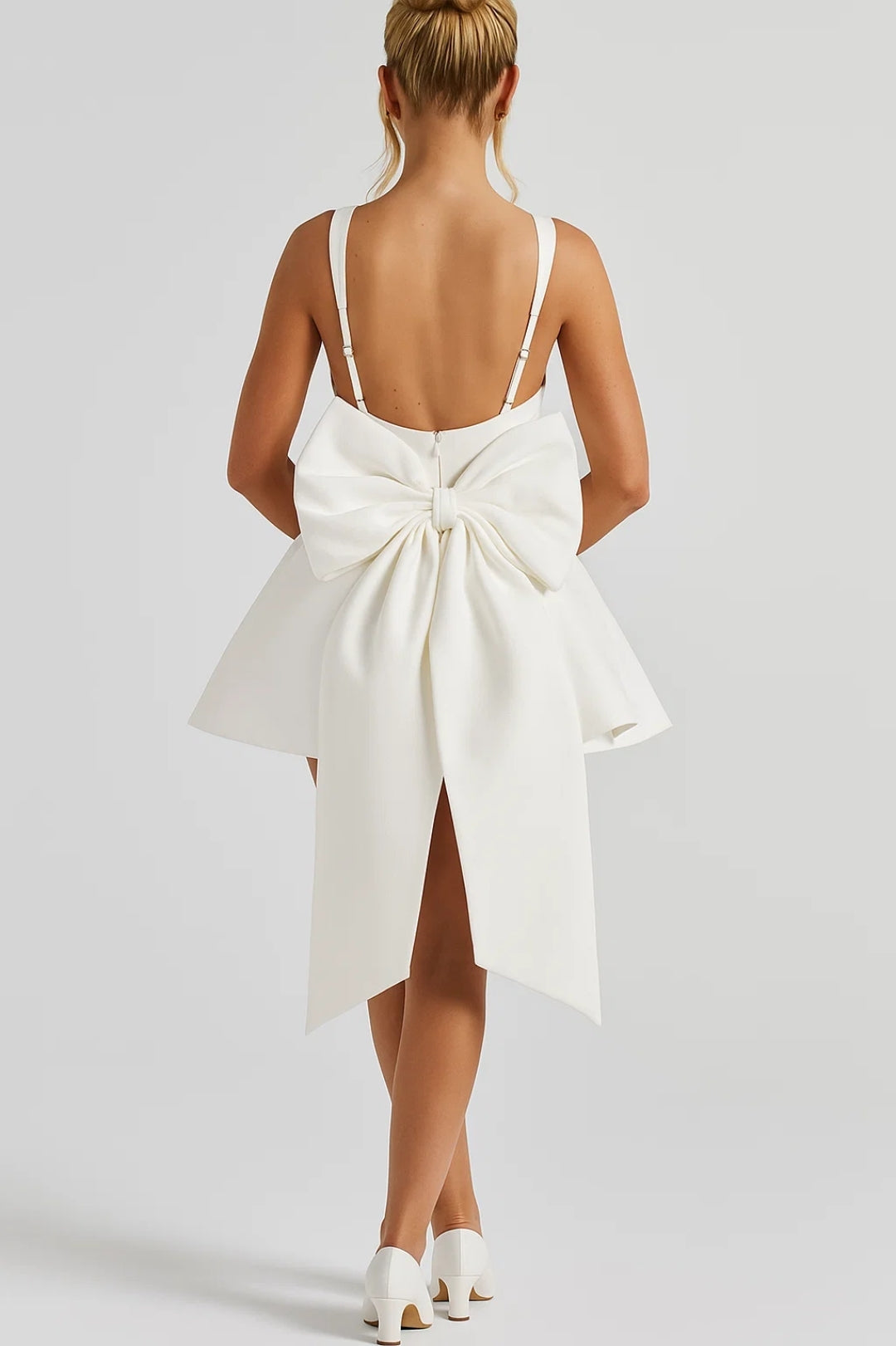 Back view of the white dress on a model, showing low open back and large bow with long tails 4