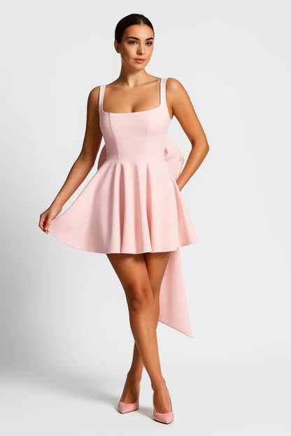 Model wearing the dress in pale pink, front view, holding the skirt out with pink heels 6