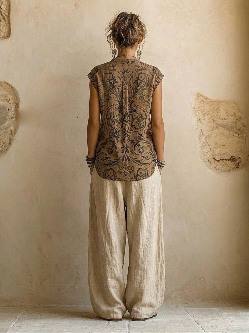 Back view of the sleeveless paisley-print top with curved hem, worn with wide beige linen trousers 3