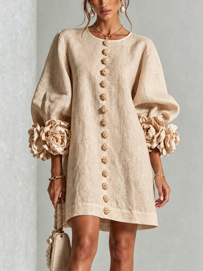 Close front view of the beige dress, showing the round neckline, floral buttons down the front and large rose cuffs. 23