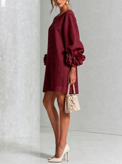 Side view of the burgundy dress on a model, showing the puffed sleeve with rose cuff and a cream handbag. 36