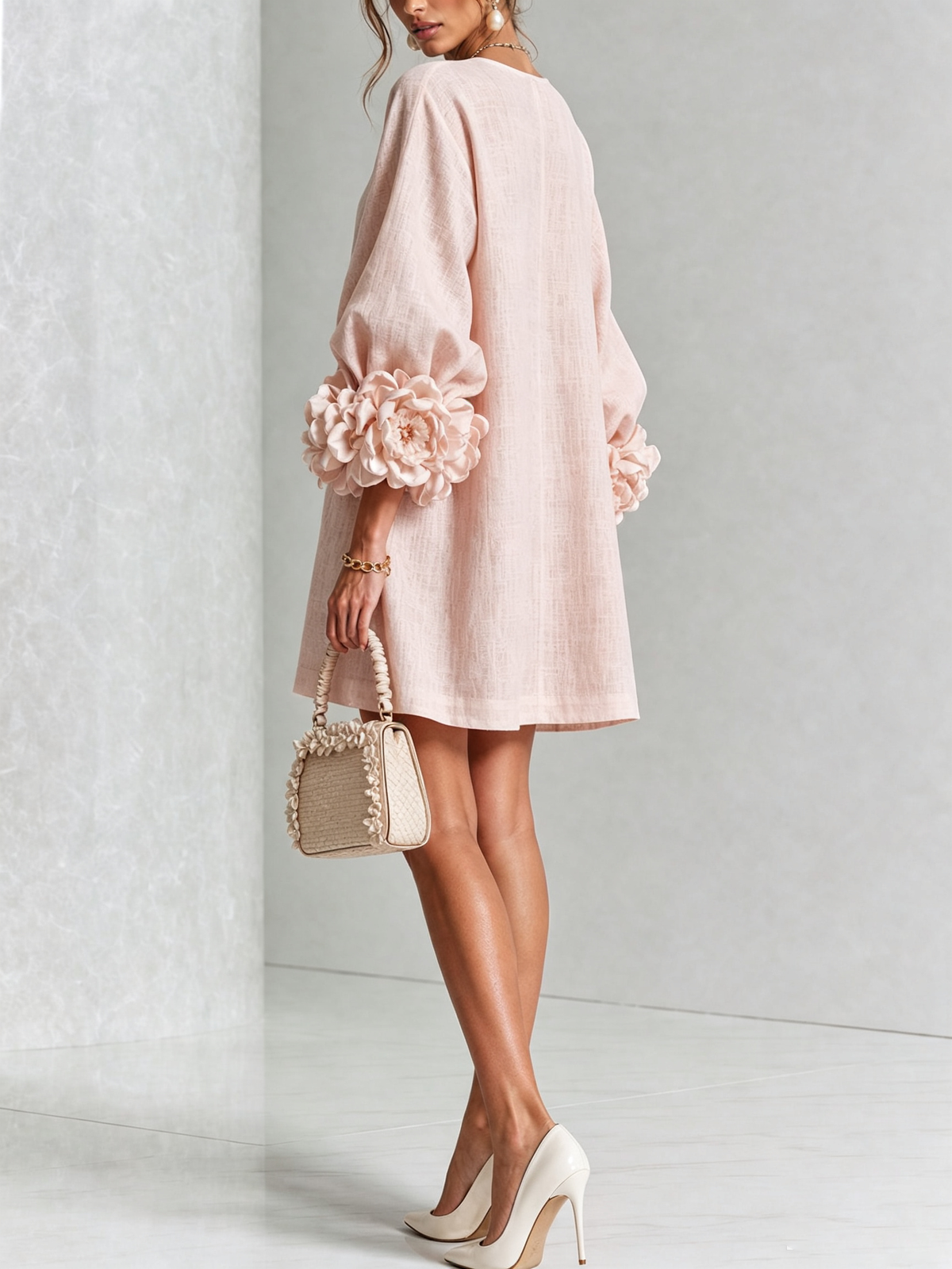 Model in the pale pink dress seen from behind, turning to show the large rose cuffs and loose back. 21