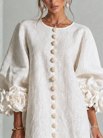 Close-up of the cream dress bodice, showing the round neckline, textured weave, flower buttons and sculpted rose cuffs. 5