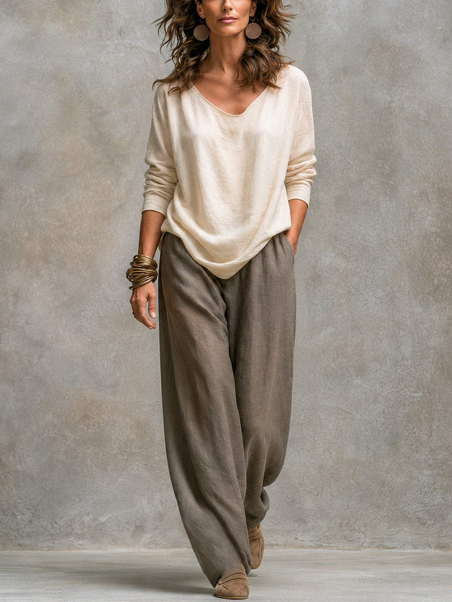 Full-length front view of the cream long-sleeved V-neck top worn with the taupe wide-leg trousers, without the jacket. 2