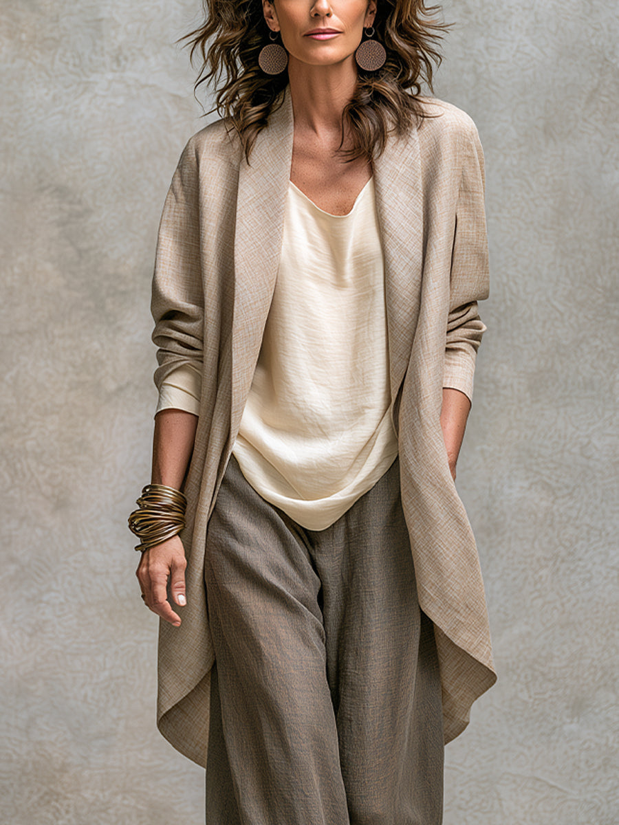 Close-up of the open long jacket with its wide lapels and curved hem, worn over the cream top. 3