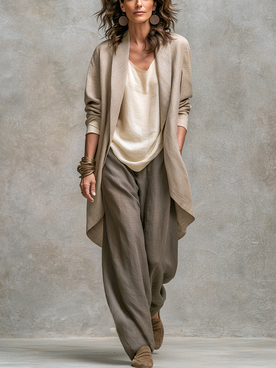 Full-length front view of a model in the open beige jacket over a cream top and loose taupe wide-leg trousers. 1