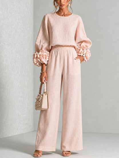 Model standing front-on in the blush pink set, hand in pocket, holding a woven handbag 1