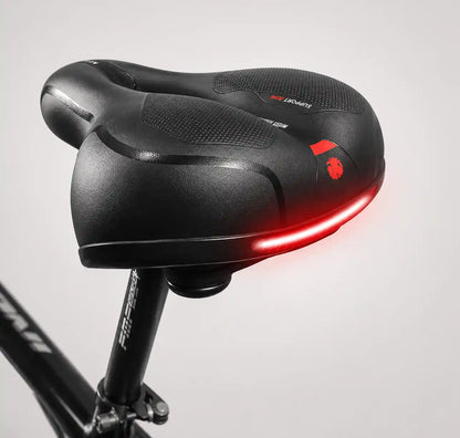Rear three-quarter view of the saddle on a seat post, with the red reflective strip glowing along the back edge. 15