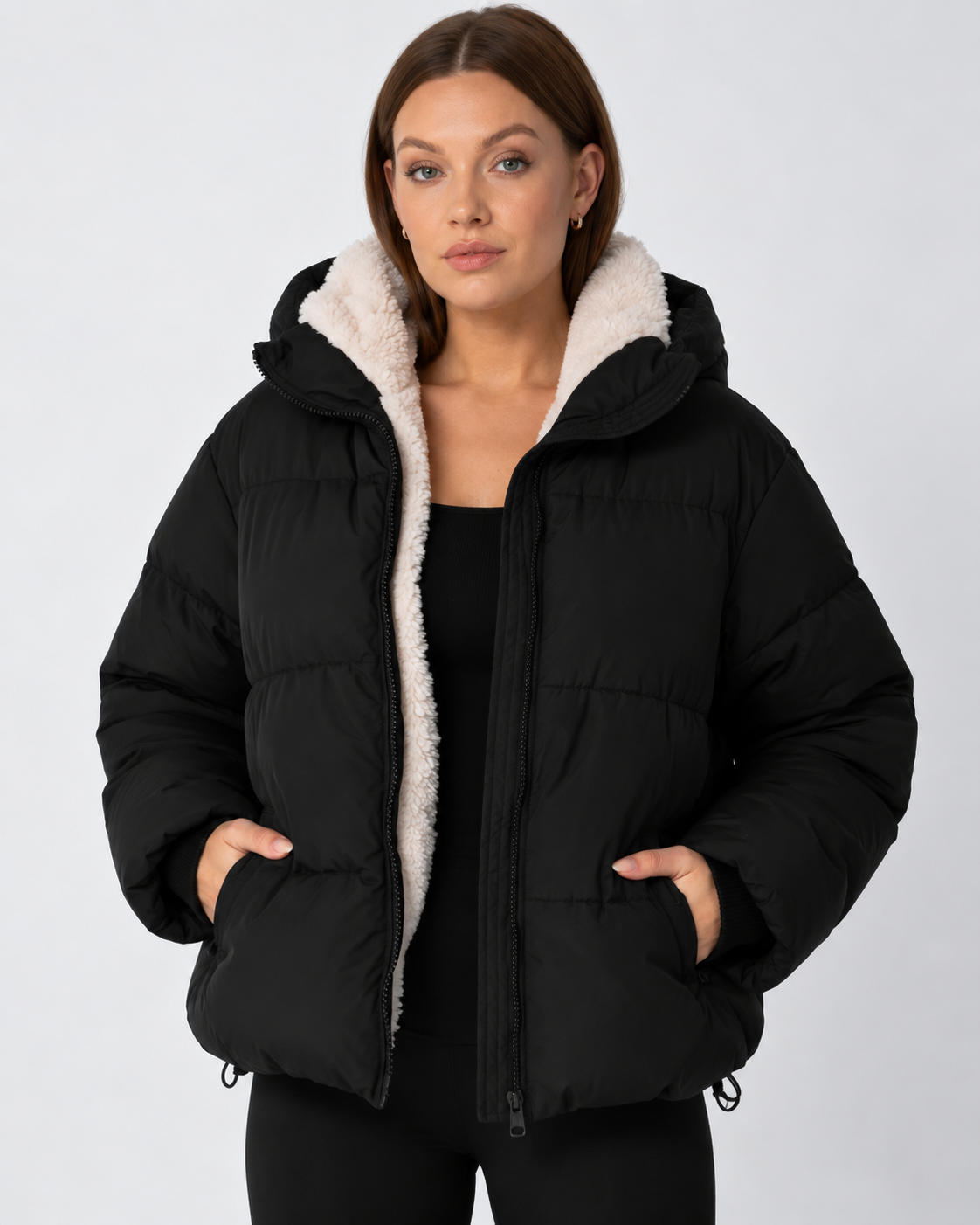 Model wears the black puffer jacket open over a black top, with cream fleece lining and hands in pockets 11