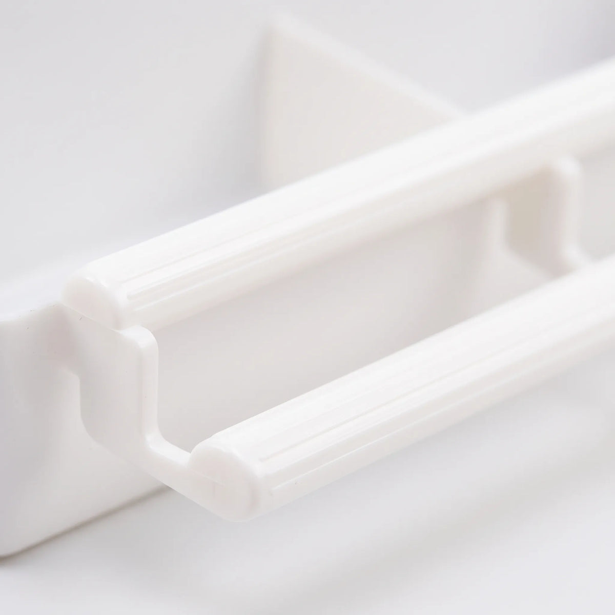Close-up of the feeder's ridged white plastic perch bars and their bracket, showing the texture and moulded construction. 3