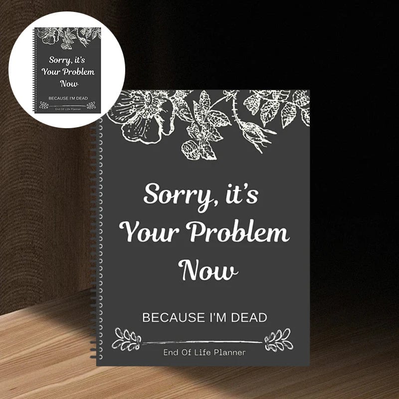 Coil-bound planner with a dark grey cover, white floral line drawings along the top and a bold centred slogan, on a wooden shelf. 10