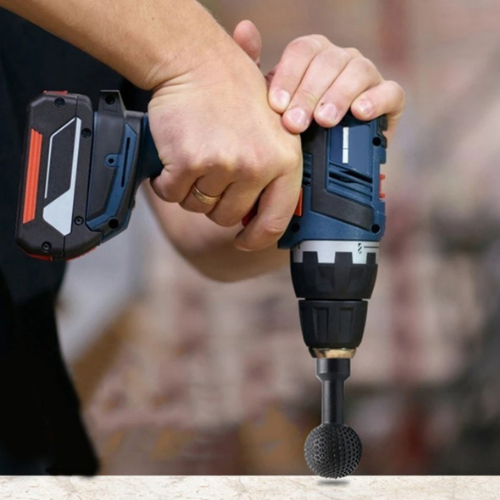 Hands gripping a cordless drill fitted with a black spherical carving bit, pointing down at a worktop 1