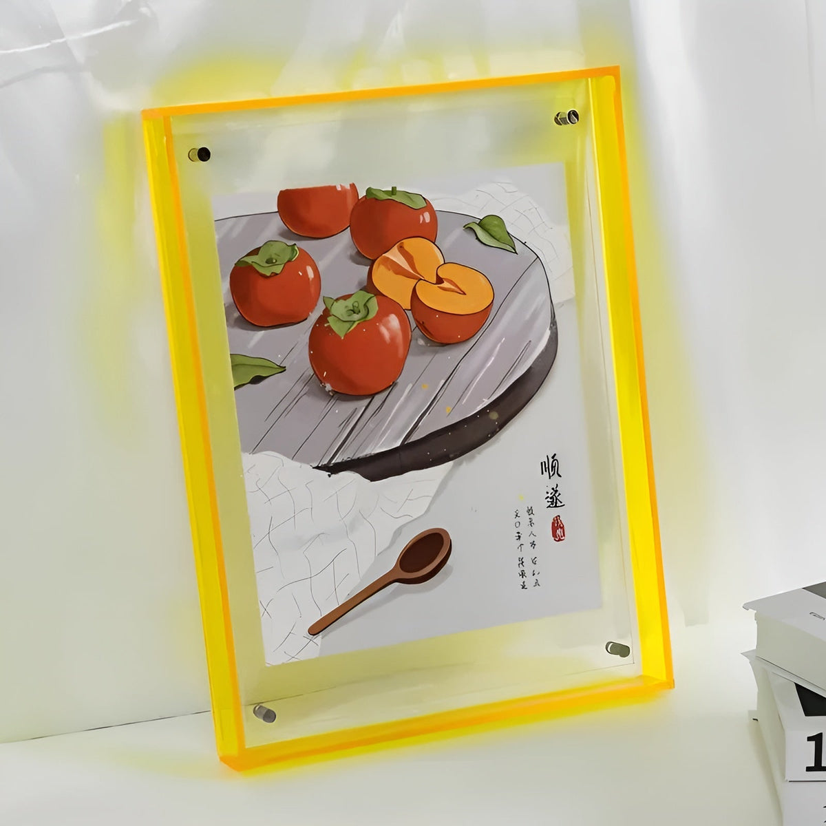 Yellow-edged acrylic frame glowing against a white wall, holding an illustration of persimmons on a plate with a wooden spoon. 12