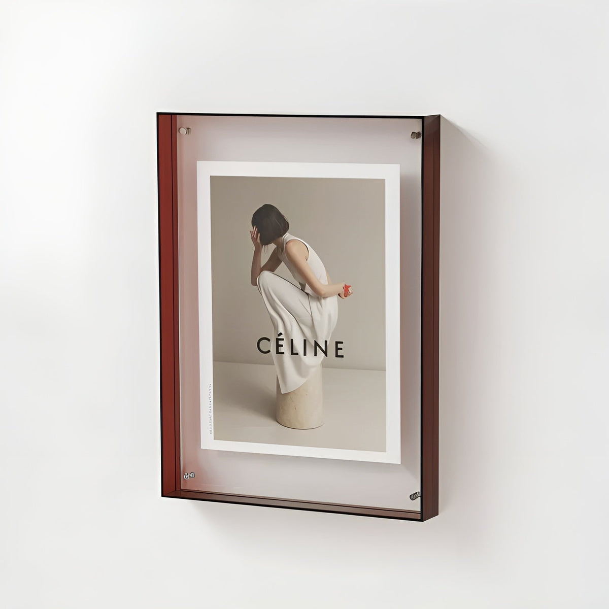 Wall-mounted acrylic frame with a dark red edge, holding a fashion print of a woman in white crouching on a stone plinth. 20