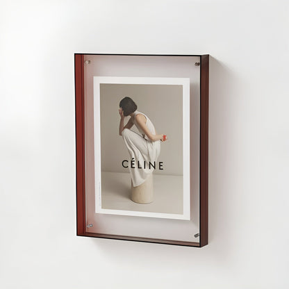 Wall-mounted acrylic frame with a dark red edge, holding a fashion print of a woman in white crouching on a stone plinth. 20