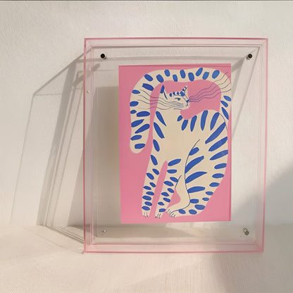 Pink-edged clear acrylic frame leaning on a wall, holding a pink print of a white cat with blue stripes. 9