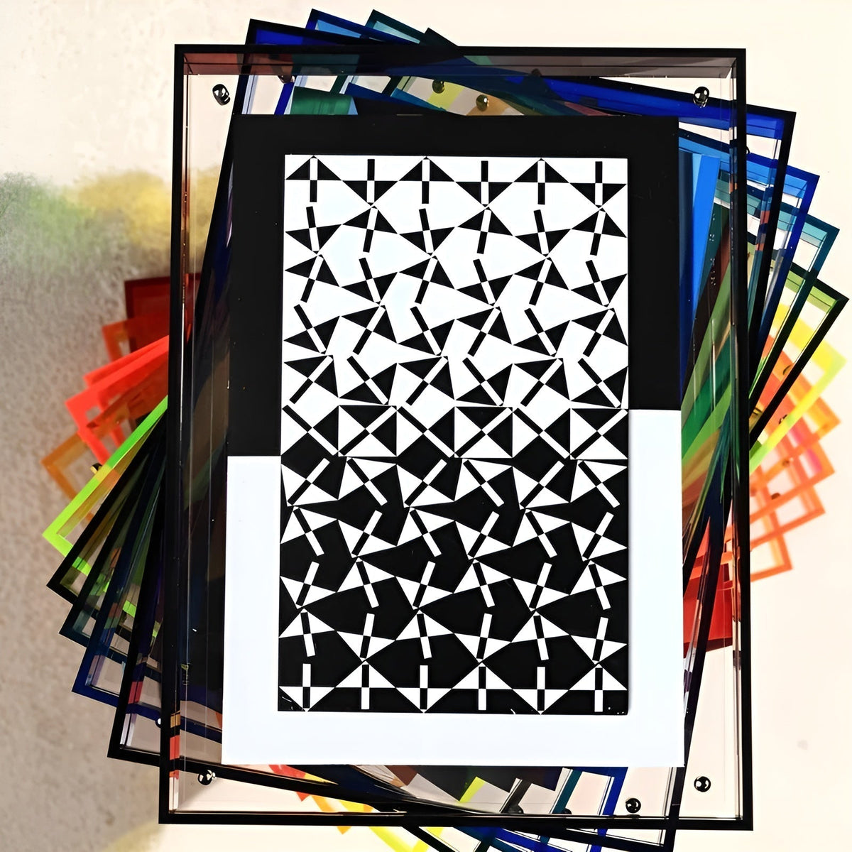 Black-bordered acrylic frame with a black and white triangle pattern on top of a fanned stack of multicoloured frames. 8