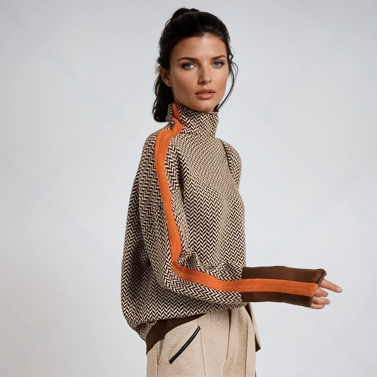 Model in profile wearing the herringbone knit jumper in brown and cream, with an orange stripe down the sleeve and cream trousers. 1